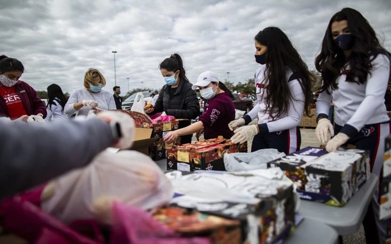 Các tình nguyện viên đeo khẩu trang trong lúc phân phối thực phẩm cứu trợ người dân tại bang Texas, Mỹ, ngày 21-2. (Ảnh: AP)
