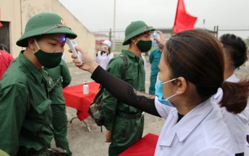 Nhân viên y tế huyện Quảng Xương kiểm tra thân nhiệt các tân binh trước lễ giao, nhận quân năm 2021.