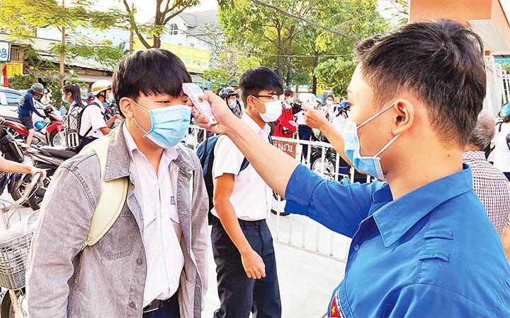 Trường THPT Nguyễn Hữu Huân đo thân nhiệt và khai báo y tế trực tuyến cho học sinh ngay tại cổng trường.