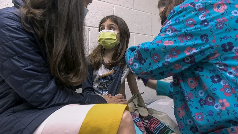 Ngày 24-3, cô bé Alejandra Gerardo, 9 tuổi, nhìn mẹ của mình, Tiến sĩ Susanna Naggie, khi cô bé được tiêm mũi vaccine Covid-19 của Pfizer đầu tiên trong một thử nghiệm lâm sàng cho trẻ em tại Đại học Duke, Mỹ. Ảnh: AP.