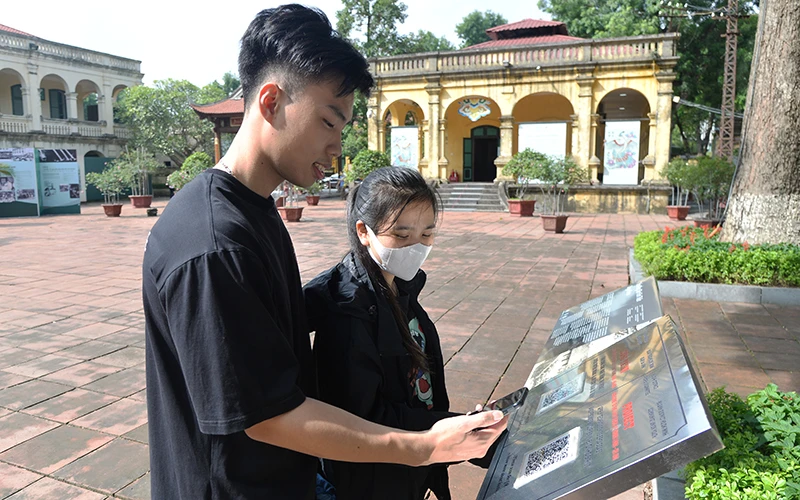 Du khách quét mã QR để tìm hiểu thông tin tại Di sản văn hóa thế giới Hoàng thành Thăng Long (Hà Nội). Ảnh: Bảo Trinh