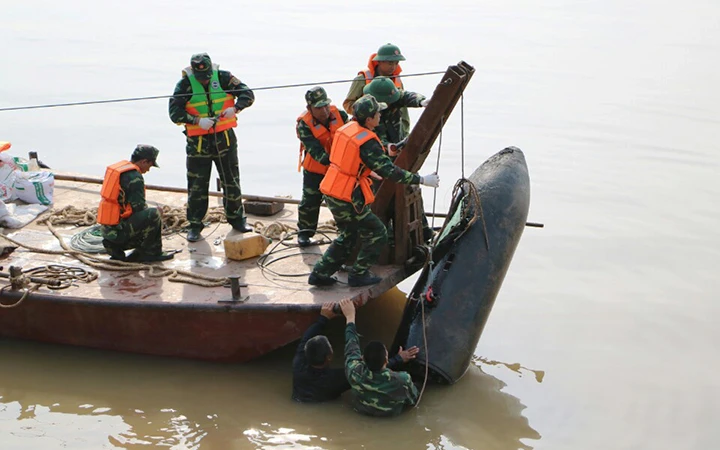 Bộ đội công binh trục vớt quả bom lớn sót lại sau chiến tranh từ lòng sông Hồng, dưới trụ cầu Long Biên (Hà Nội).