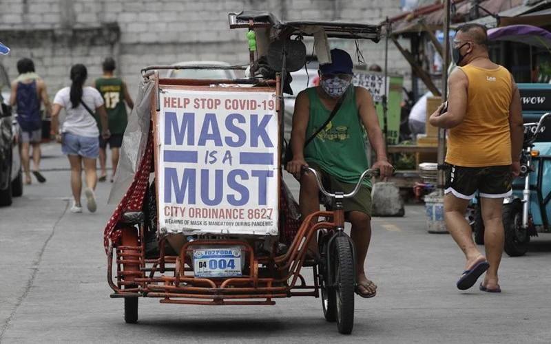 Người đàn ông tại Manila đạp xe với khẩu hiệu nhắc nhở người dân đeo khẩu trang. (Ảnh: AP)