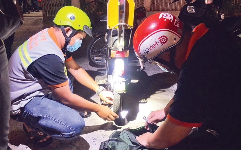 Thành viên đội Hỗ trợ nhân dân quận Bình Tân giúp đỡ người đi đường bị hư xe trong đêm.