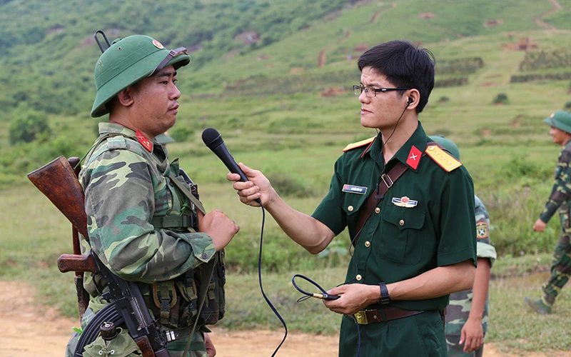 Phóng viên phát thanh quân đội nhân dân tác nghiệp tại thao trường huấn luyện.