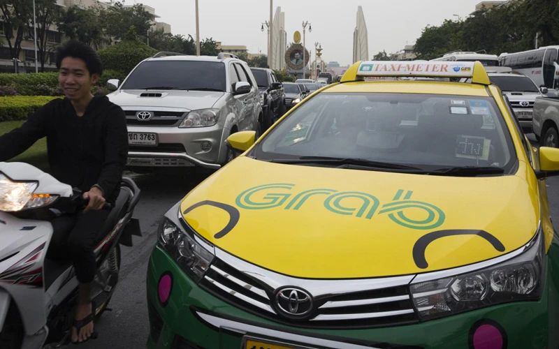 Một chiếc xe taxi dán biểu tượng ứng dụng gọi xe trực tuyến Grab lưu thông tại Thái Lan (Ảnh Bloomberg)