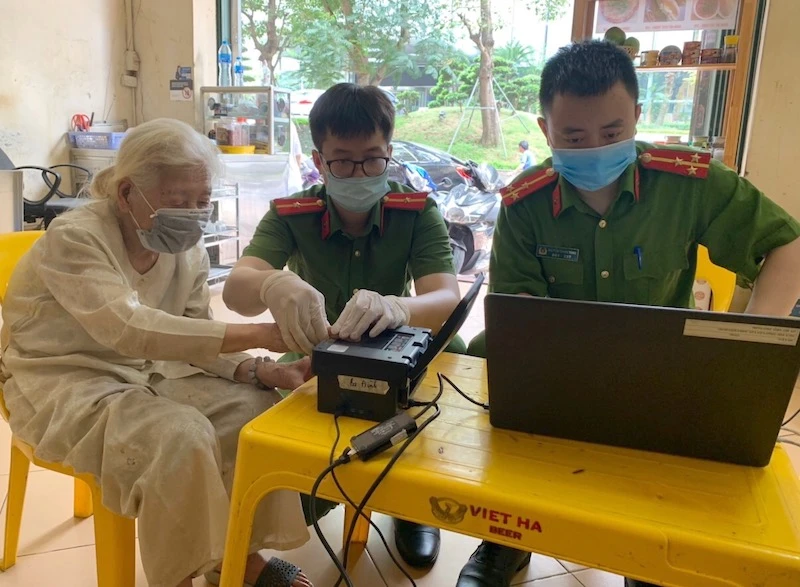 Các đồng chí trong tổ cấp CCCD, Công an quận Ba Đình, thực hiện lấy dấu vân tay tại nhà cho cụ Phạm Thị Mỹ.