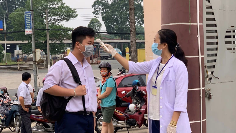 Cán bộ y tế đo thân nhiệt cho thí sinh tại Hội đồng thi Trường THCS Nguyễn Thị Minh Khai, TP Thủ Dầu Một.