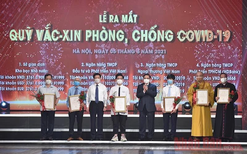 Thủ tướng Phạm Minh Chính và các đồng chí lãnh đạo trao chứng nhận và tặng hoa cho các tập thể, cá nhân đã đóng góp ủng hộ Quỹ Vaccine phòng, chống Covid-19, tối 5-6. (Ảnh: TRẦN HẢI)