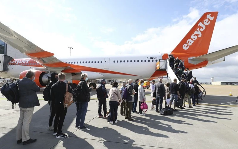 Hành khách chuẩn bị lên máy bay khởi hành từ sân bay Gatwick, Anh, tới Bồ Đào Nha, ngày 17-5. (Ảnh: AP)