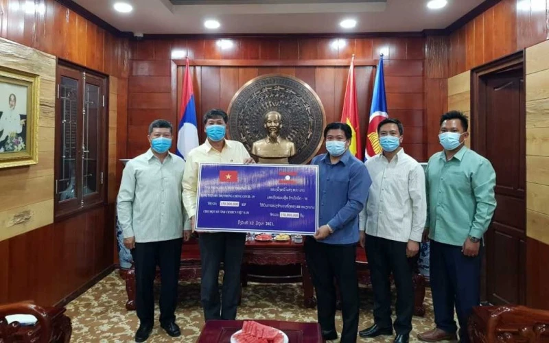 Đồng chí Bouahong Khamha (phải) trao 150 triệu kíp Lào để ủng hộ, đóng góp vào Quỹ vaccine phòng, chống Covid-19, ngày 12-6.