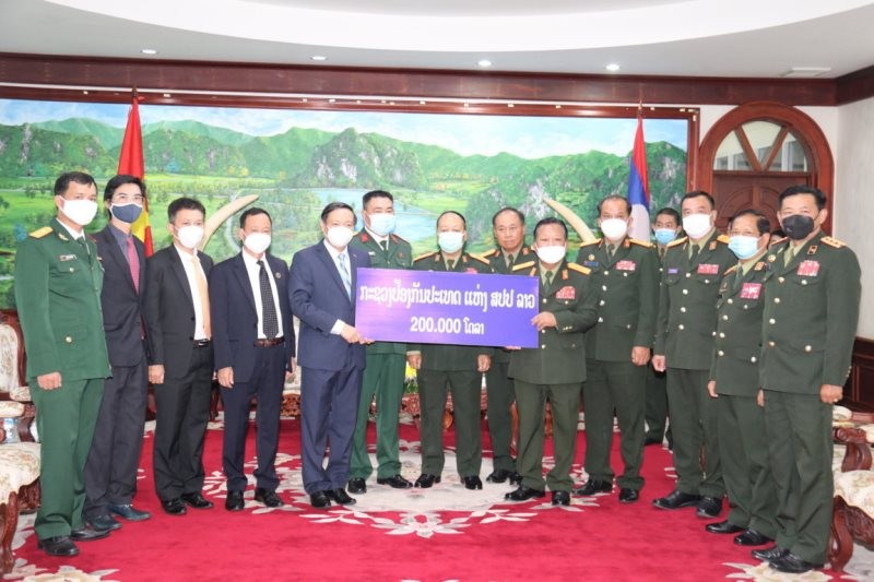 Đại sứ Nguyễn Bá Hùng (trái) đón nhận món quà quý báu mà Bộ Quốc phòng Lào ủng hộ Quỹ phòng, chống dịch Covid-19 của Việt Nam.