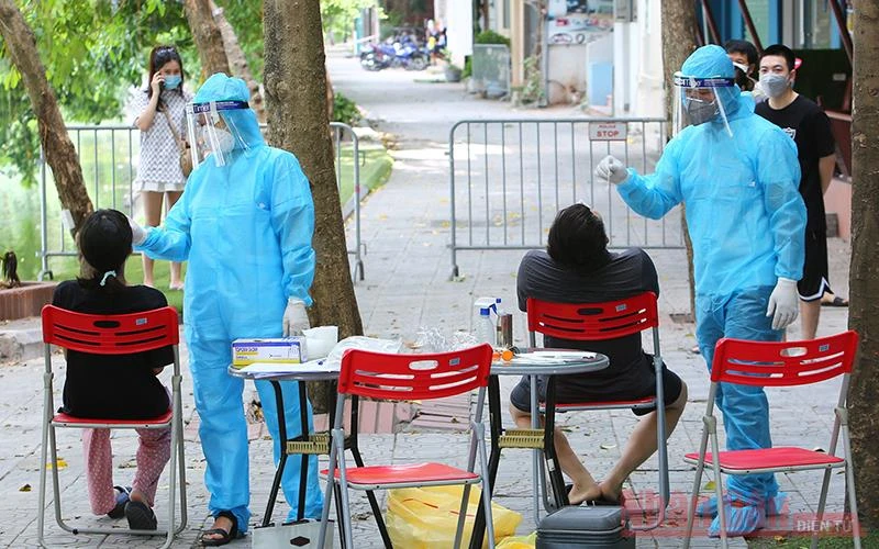 Nhân viên y tế lấy mẫu xét nghiệm người dân tại khu vực cách ly y tế phường Nam Đồng - quận Đống Đa. (Ảnh: DUY LINH)
