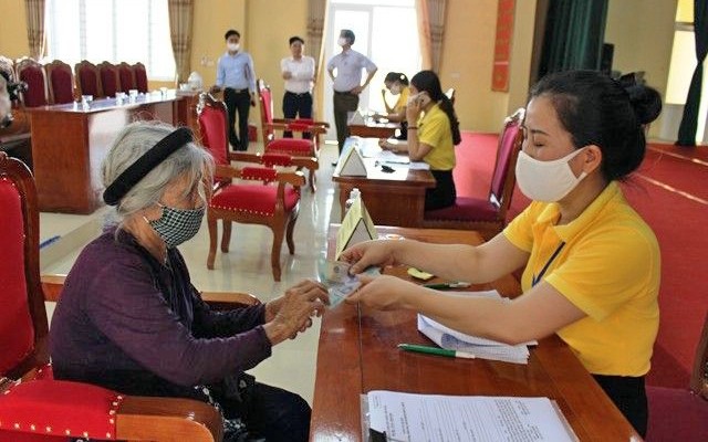 Nhân viên bưu điện cấp phát tiền hỗ trợ người dân xã Ðông Vinh, TP Thanh Hóa (tỉnh Thanh Hóa) gặp khó khăn do Covid-19. Ảnh: MAI LUẬN