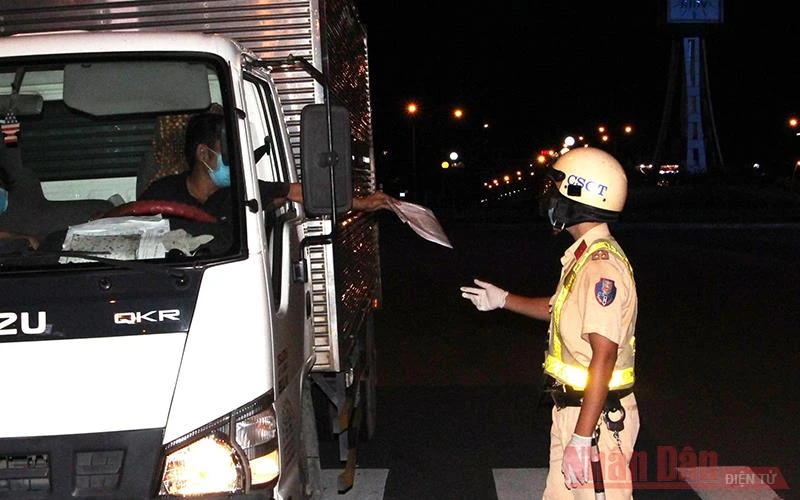 Lực lượng Cảnh sát giao thông Công an thành phố Hồ Chí Minh kiểm tra một lái xe tải tại Trạm kiểm dịch đặt trên đường Điện Biên Phủ, quận 1 vào tối ngày 26/7. 