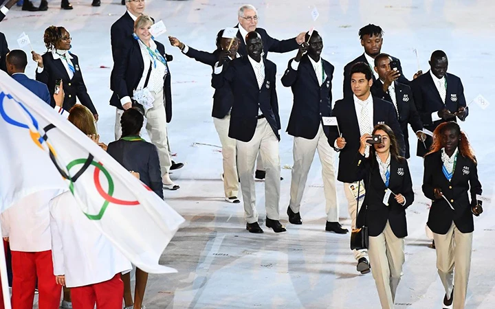 Đội Olympic tị nạn diễu hành qua lễ đài.