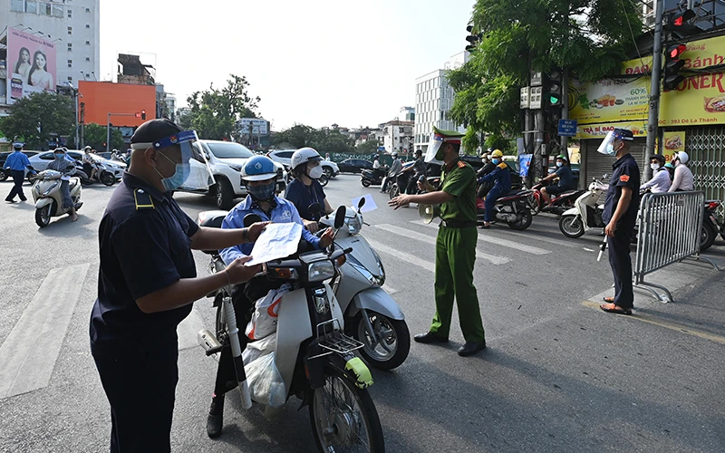Lực lượng chức năng kiểm tra giấy tờ của người dân khi tham gia giao thông tại chốt phòng, chống dịch trên phố Đê La Thành (quận Ba Đình, Hà Nội). Ảnh: MINH HÀ