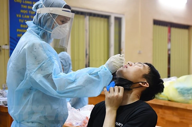 Trung tâm Y tế quận Ba Đình lấy mẫu xét nghiệm cho các tiểu thương và nhân viên Ban Quản lý chợ Long Biên. (Ảnh: TTXVN)
