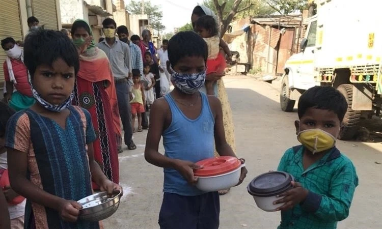 Trẻ em xếp hàng nhận gạo và đậu cứu trợ tại một khu ổ chuột ở khu Kapasheda, Delhi, ngày 7/4. Ảnh: Al Jazeera.