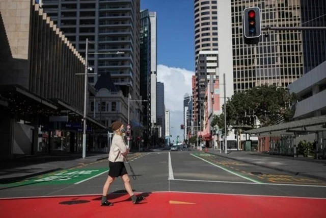 Một phụ nữ đeo khẩu trang đi trên đường phố Auckland, New Zealand ngày 18/8. 