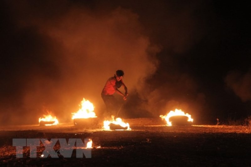Người biểu tình Palestine đốt cháy lốp xe trong cuộc đụng độ với binh sĩ Israel tại Dải Gaza, ngày 28/8. (Ảnh: THX/TTXVN)