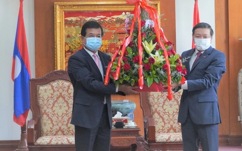 Đại sứ Nguyễn Bá Hùng (phải) đón nhận lẵng hoa tươi thắm của đồng chí Somphone Sichaleune, Phó trưởng Ban Đối ngoại Trung ương Đảng Nhân dân Cách mạng Lào.