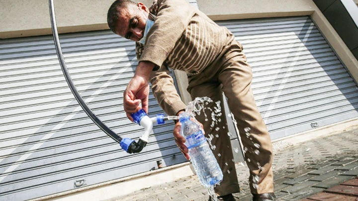 Một người đàn ông đang lấy nước từ máy chiết xuất. Ảnh: THE BANGKOK POST