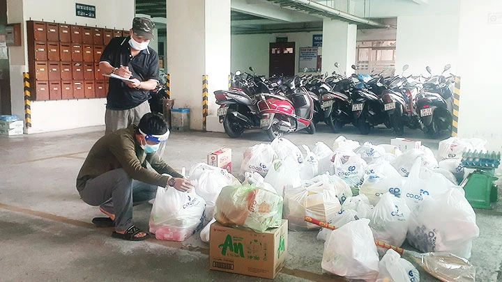 Cư dân tại tòa nhà 159 Điện Biên Phủ, phường 15, quận Bình Thạnh nhận thực phẩm đi chợ giúp dân của Ban quản lý chung cư.