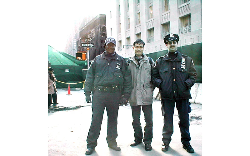 Tác giả chụp ảnh với cảnh sát thành phố New York, phía sau là tòa Tháp đôi WTC bị khủng bố đánh sập ngày 11/9/2001 (ảnh chụp tháng 11/2001). 