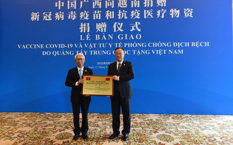 Đại sứ Việt Nam tại Trung Quốc Phạm Sao Mai (trái) thay mặt tiếp nhận số hàng viện trợ từ Phó Chủ tịch Chính quyền Khu tự trị Dân tộc Choang Quảng Tây Hoàng Tuấn Hoa. (Ảnh: Mạnh Cường - TTXVN)