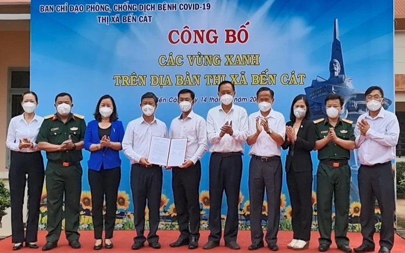Chủ tịch UBND tỉnh Bình Dương Võ Văn Minh (thứ 4 từ trái sang) trao quyết định công bố “vùng xanh” cho lãnh đạo thị xã Bến Cát. 
