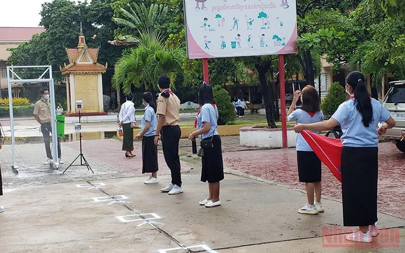Học sinh một trường THPT tại Phnom Penh thực hiện đo thân nhiệt và khử khuẩn theo quy định.