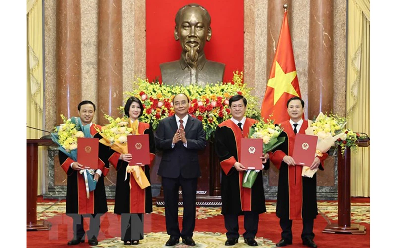 Chủ tịch nước Nguyễn Xuân Phúc trao quyết định và tặng hoa chúc mừng 4 thẩm phán Tòa án Nhân dân tối cao. (Ảnh: TTXVN) 