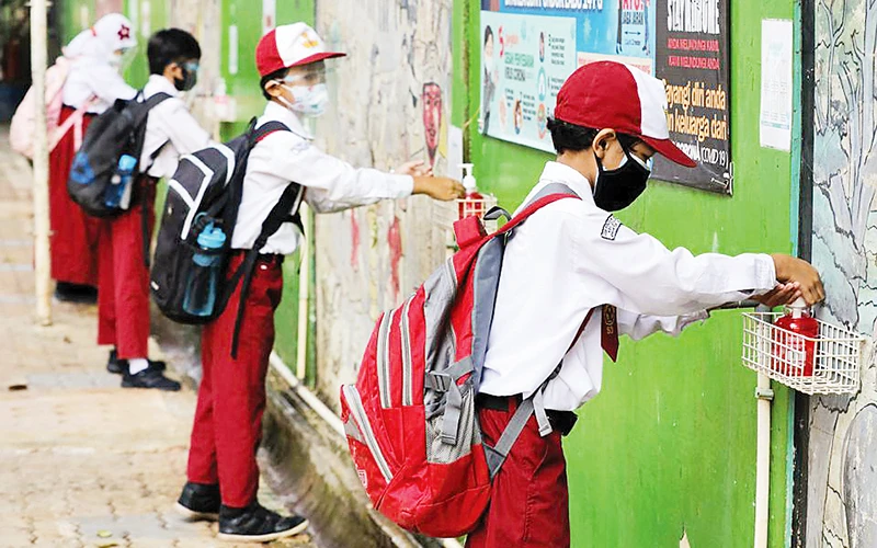 Học sinh Indonesia sát khuẩn tay trước khi vào lớp.