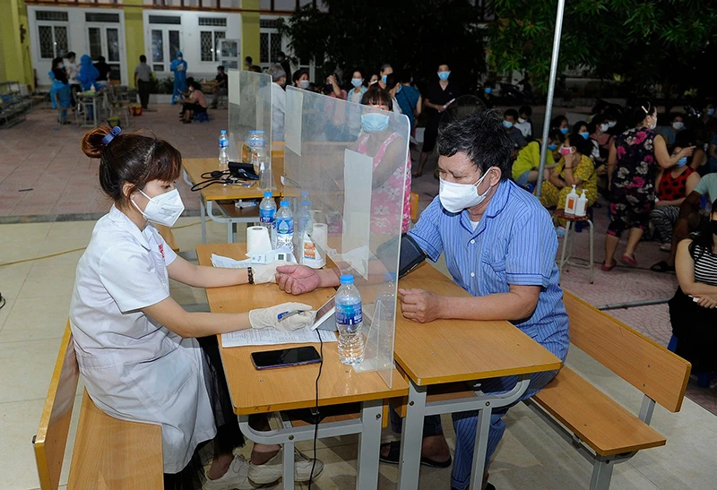 Khám sàng lọc trước khi tiêm vắc-xin phòng Covid-19 tại điểm tiêm phòng Trường THCS Vĩnh Hưng, quận Hoàng Mai (Hà Nội). Ảnh: NGUYỄN ĐĂNG