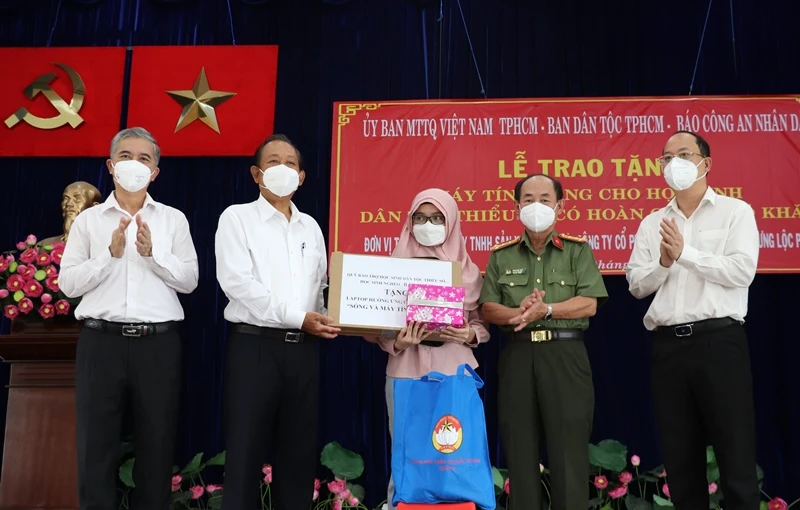 Nguyên Phó Thủ tướng Thường trực Chính phủ Trương Hòa Bình (thứ 2 từ trái qua) và đại diện các đơn vị trao tặng thiết bị học tập trực tuyến cho các em học sinh dân tộc Chăm tại quận 8.