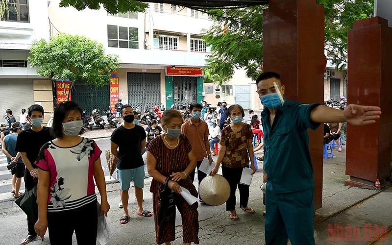 Phân luồng người dân xếp hàng tiêm vaccine Covid-19 tại Hà Nội. (Ảnh: DUY LINH)