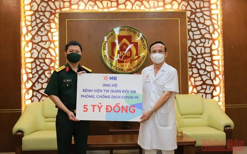 Phó Tổng giám đốc MBbank, Đại tá Trần Minh Đạt (bên trái) trao tặng ủng hộ cho đại diện Bệnh viện Trung ương Quân đội 108. (Ảnh: HỒNG ANH).