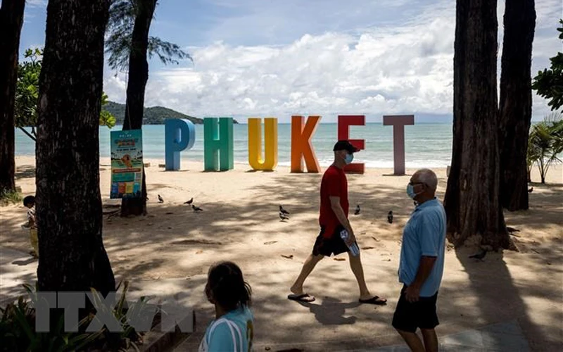 Du khách dạo chơi trên bãi biển ở Phuket, Thái Lan ngày 14/8/2021. (Ảnh: AFP/TTXVN)
