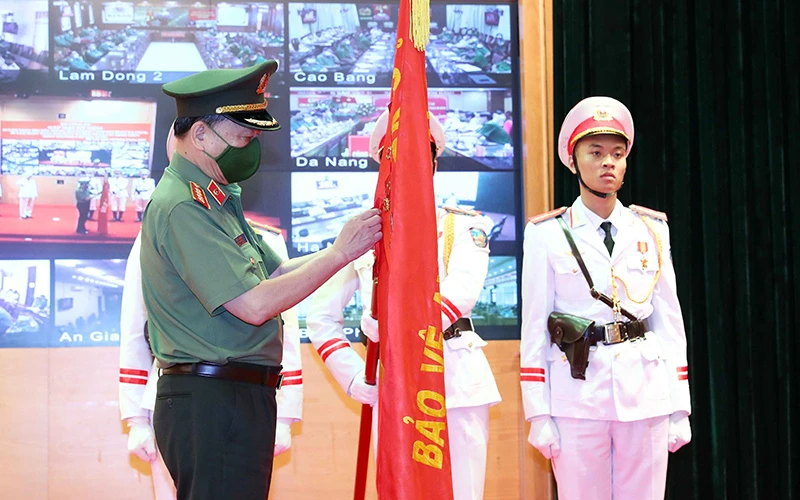 Đồng chí Tô Lâm thừa Ủy quyền của Chủ tịch nước gắn Huân chương Quân công hạng nhì lên cờ truyền thống của Cục Cảnh sát Phòng cháy chữa cháy và cứu nạn cứu hộ.Ảnh TTXVN