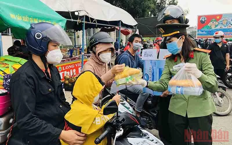 Nữ chiến sĩ Công an tỉnh Đồng Nai phát thức ăn, nước uống cho người dân về quê.