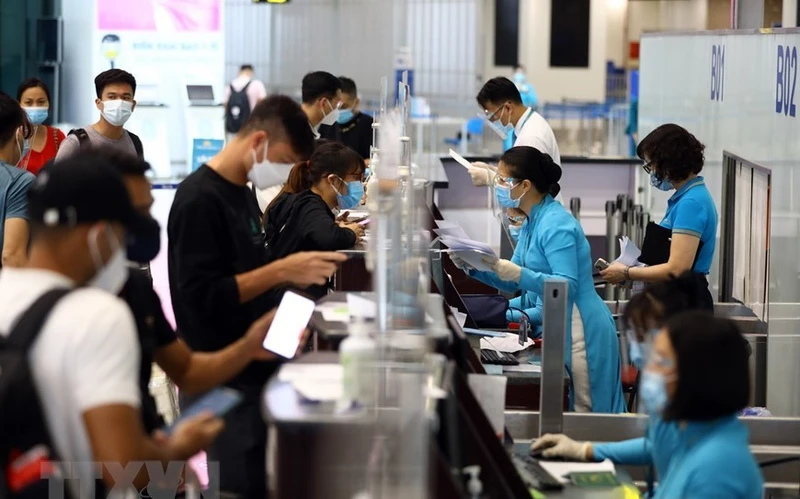 Nhân viên của Vietnam Airlines kiểm tra giấy tờ của hành khách trước khi vào làm thủ tục. (Ảnh: TTXVN)