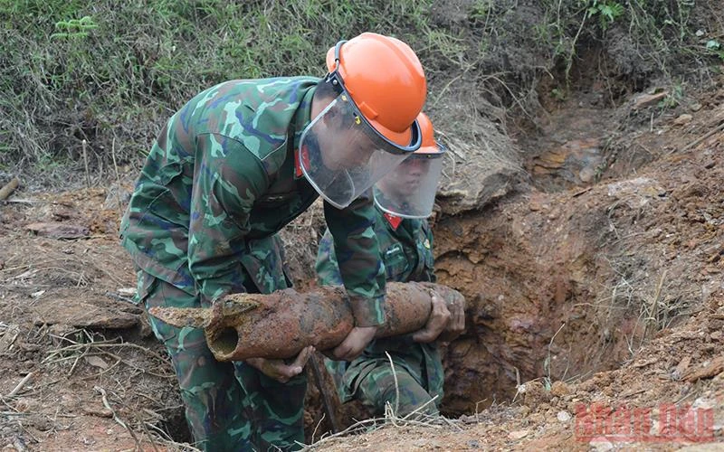 Lực lượng chức năng tiến hành rà phá vật nổ trong vườn nhà ông Nguyễn Văn Nho.