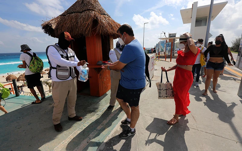 Khách du lịch sát khuẩn trước khi vào bãi biển Cancun của Mexico. Ảnh: EFE