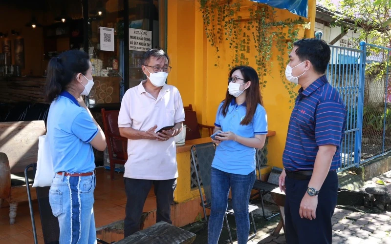 Lãnh đạo TP Long Khánh (Đồng Nai) cùng tình nguyện viên hướng dẫn ông Nguyễn Anh Tuấn sử dụng quét mã QR.