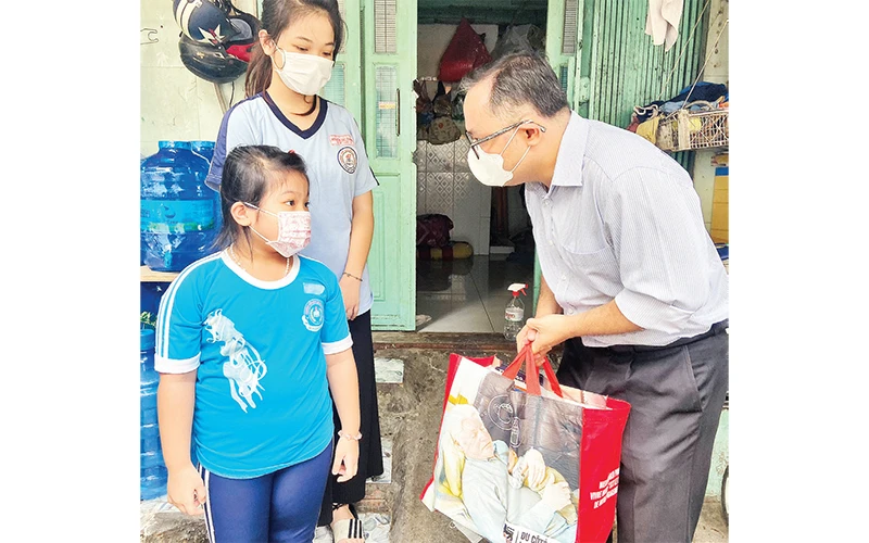 Anh Nguyễn Tuấn Anh (người bên phải) trong một lần trao quà cho trẻ em mồ côi do dịch Covid-19 trên địa bàn quận Bình Tân.Ảnh: Mạnh Linh