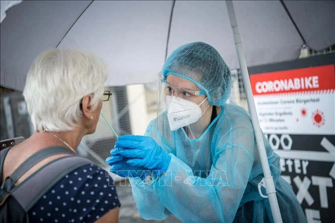 Nhân viên y tế lấy mẫu xét nghiệm COVID-19 cho người dân tại Berlin, Đức, ngày 30/7/2021. Ảnh: AFP/TTXVN