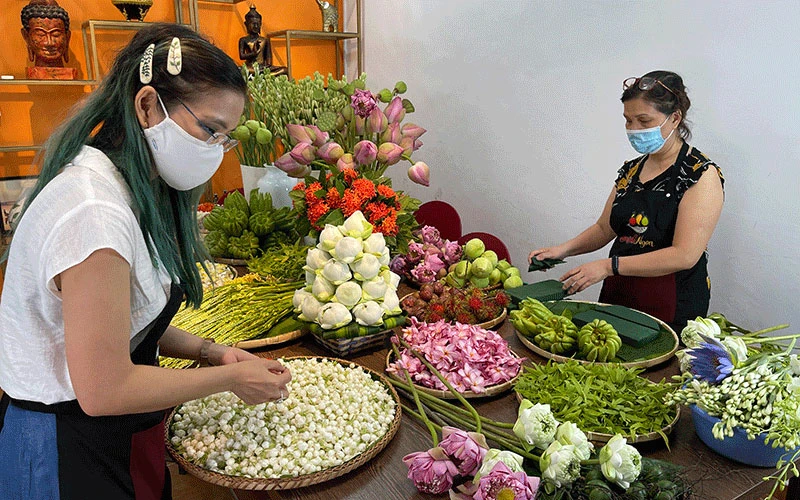 Bùi Băng Giang (trái) cùng đồng nghiệp sắp hoa vào mẹt. 