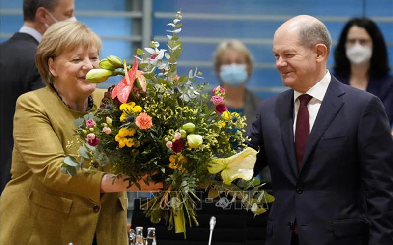 Ông Olaf Scholz tặng hoa cho Thủ tướng sắp mãn nhiệm Angela Merkel trước cuộc họp nội các ở Berlin, Đức, ngày 24/11/2021. (Ảnh: TTXVN)