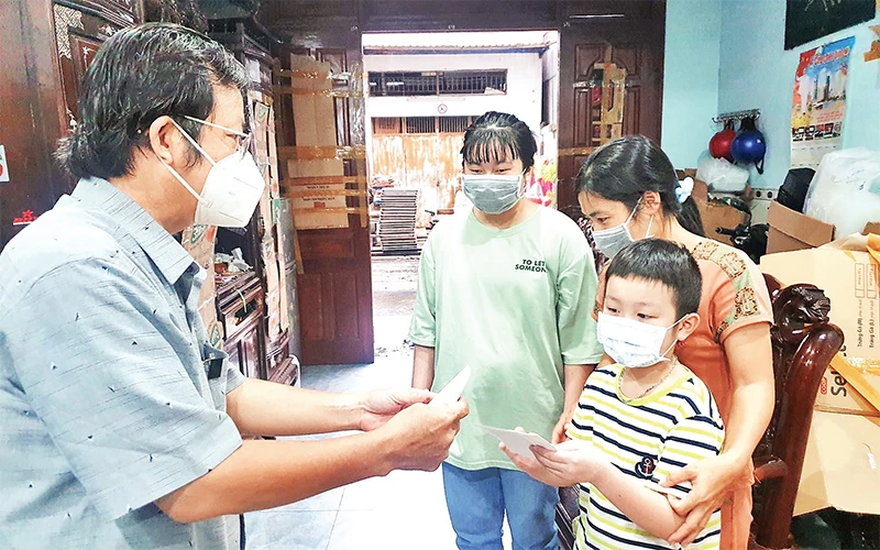 Ðại diện Ban Tuyên giáo Quận ủy Tân Phú tặng quà cho trẻ em mồ côi do dịch Covid-19 tại phường Hiệp Tân. Ảnh tư liệu do quận Tân Phú cung cấp 